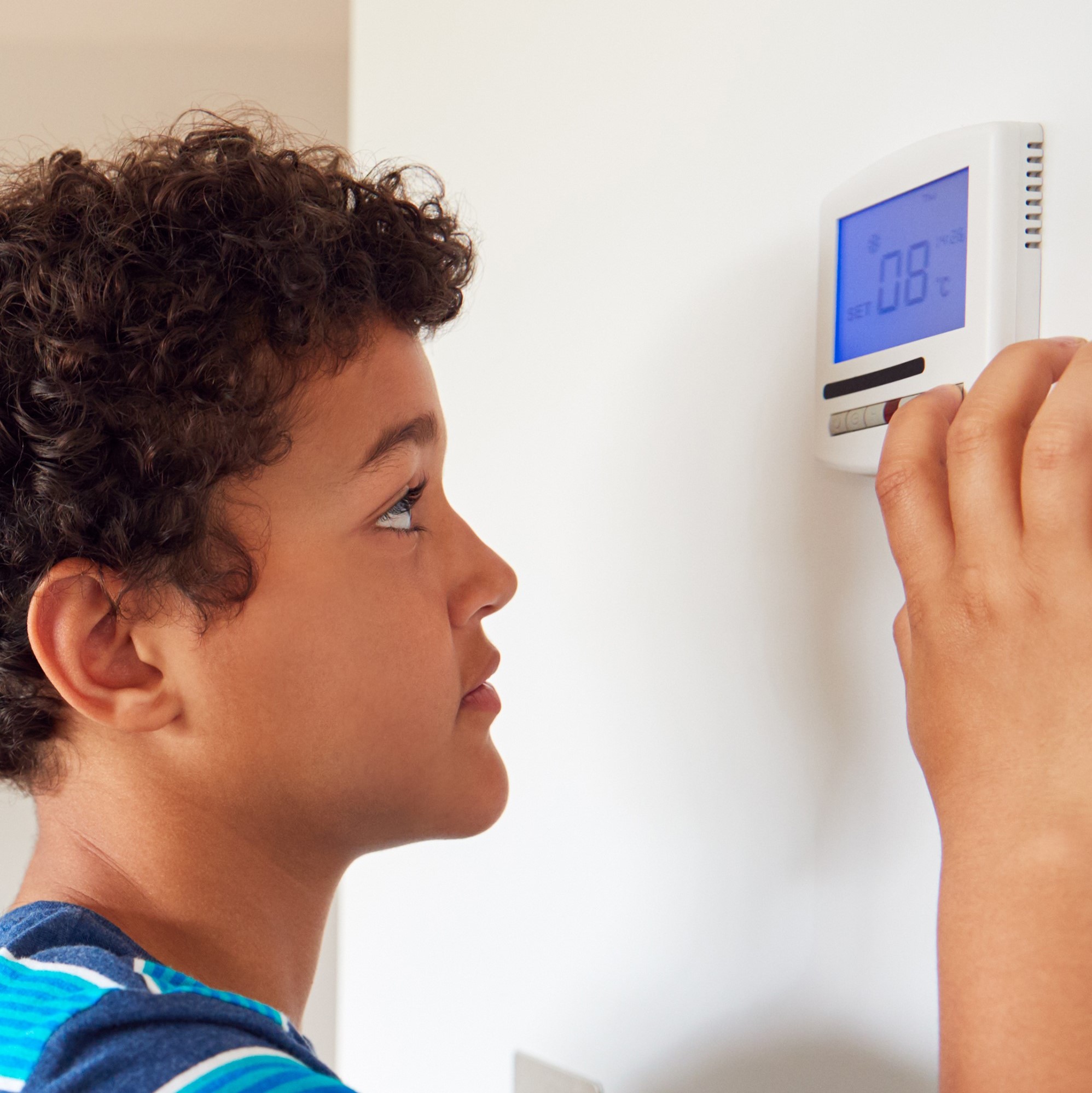 boy adjusting home thermostat