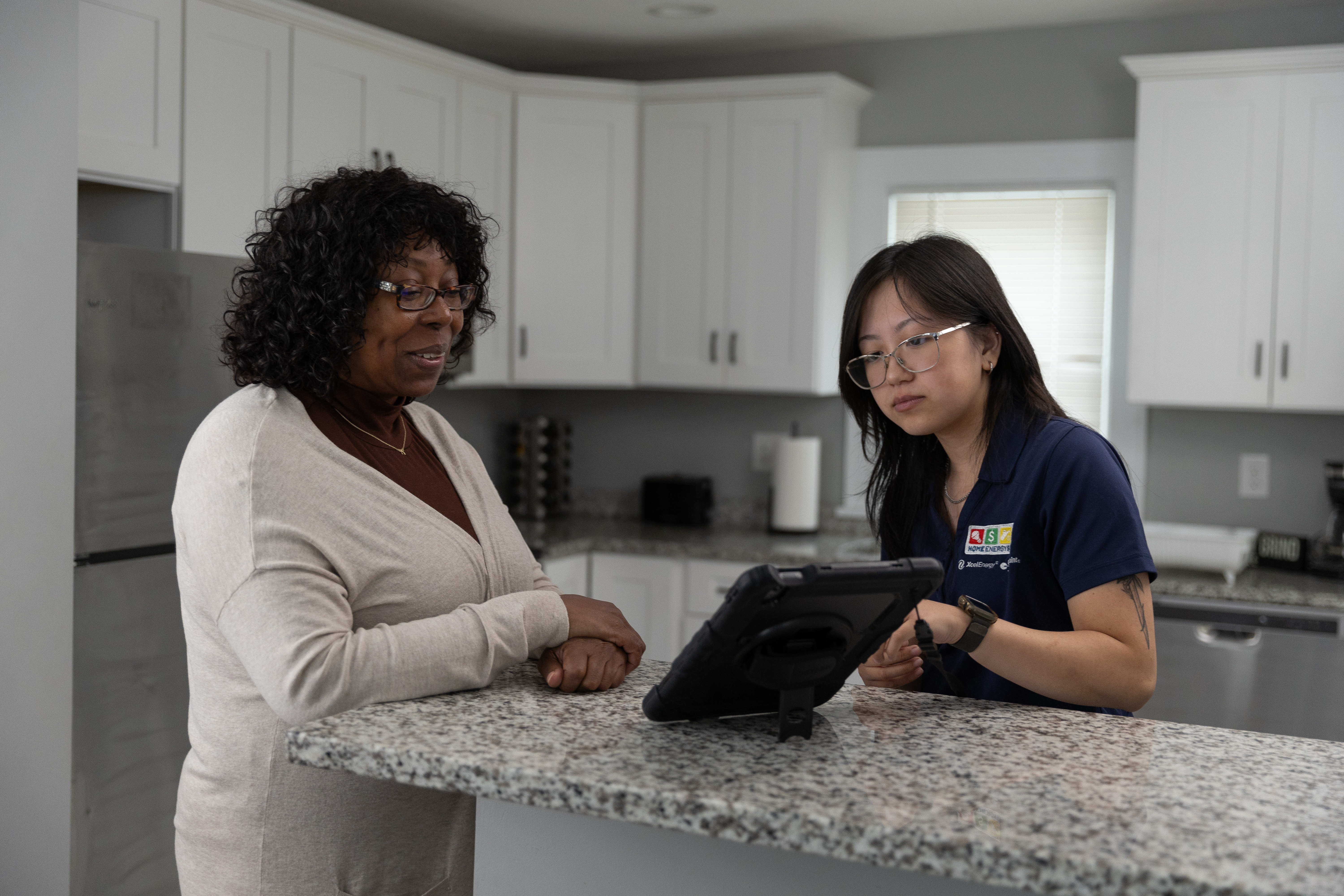 An HES Auditor and a homeowner standing at a kitchen peninsula reviewing the home's audit findings.