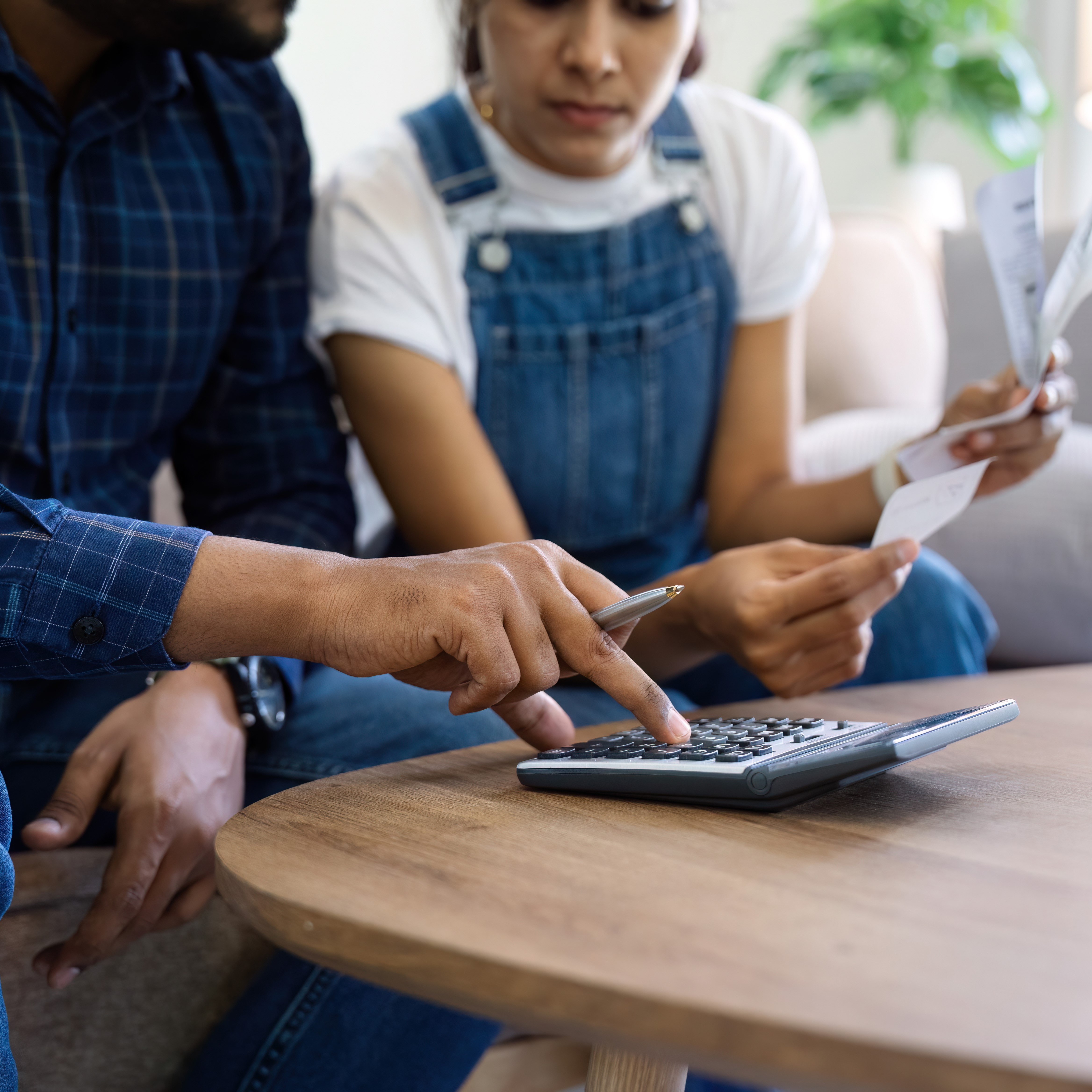 couple sitting in home and looking at bills and a calculator