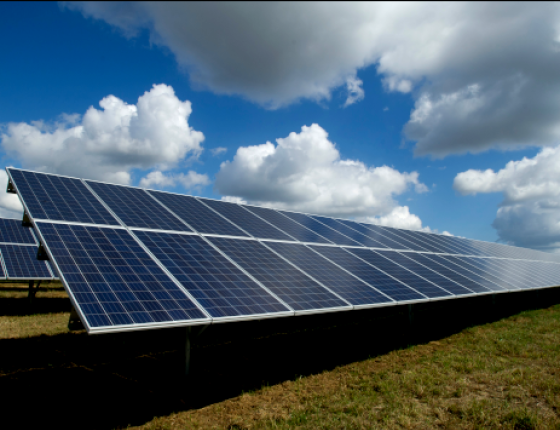 solar panels on grass with blue sky and clouds above