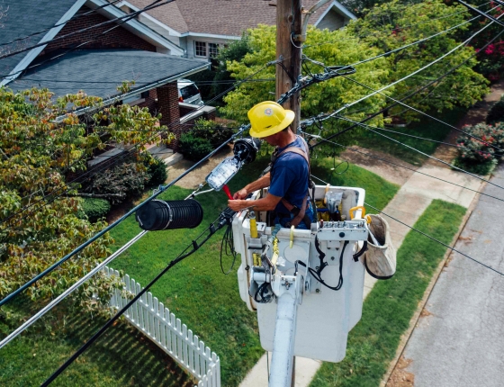 utility worker adjusting power line in residential neighborhood