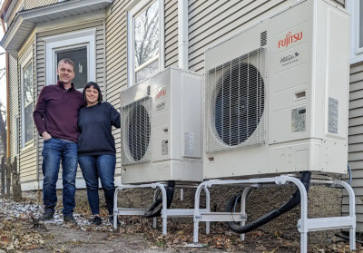 couple standing beside new heat pump units