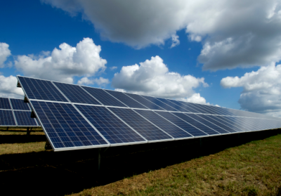 solar panels on grass with blue sky and clouds above