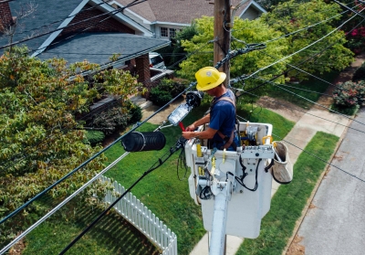 utility worker adjusting power line in residential neighborhood