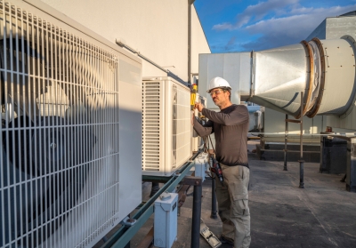 worker adjusting commercial HVAC system