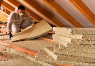 person laying insulation in attic