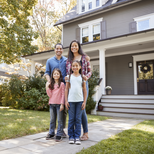 Family standing smiling in front of their house