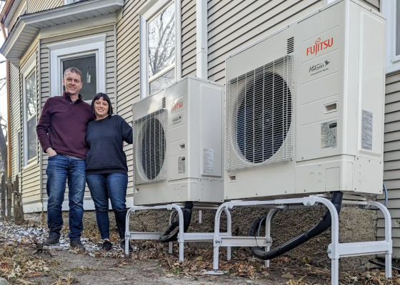 couple standing beside new heat pump units