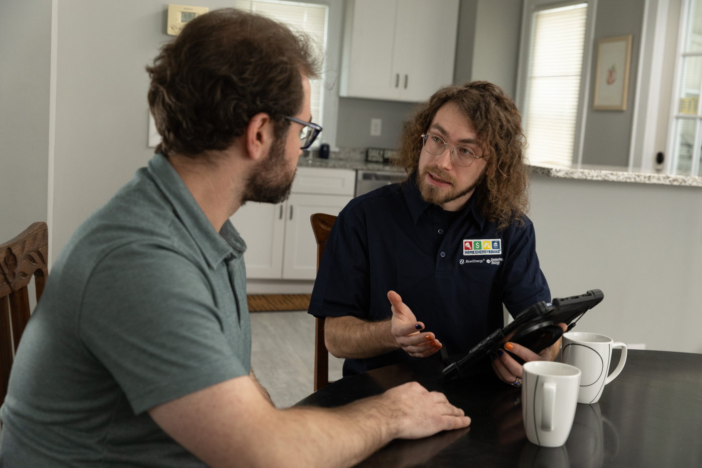 Home Energy Squad auditor reviewing energy assessment with homeowner using tablet