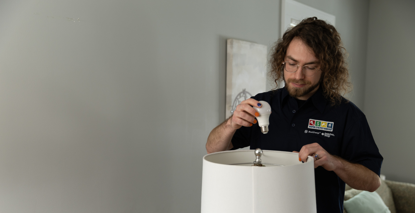 An HES auditor standing behind a lamp to change the lightbulb to an LED.