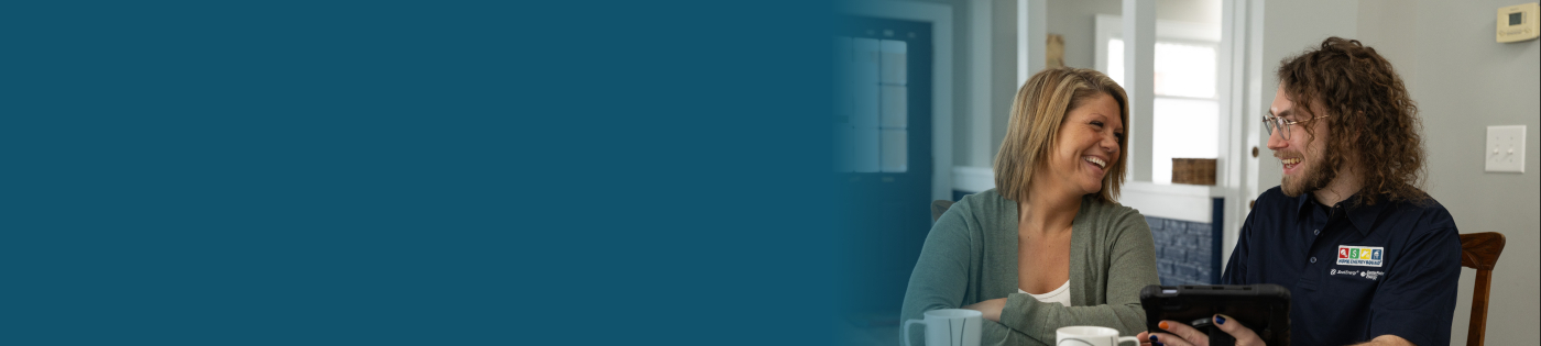 A homeowner and auditor sit in the home reviewing the home's audit findings on an iPad.