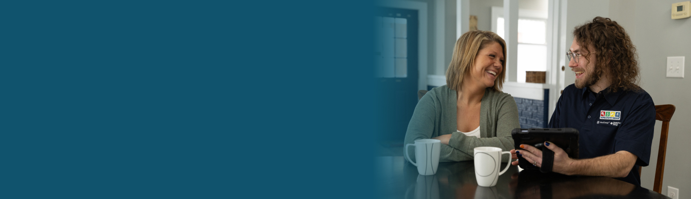 A homeowner and auditor sit in the home reviewing the home's audit findings on an iPad.