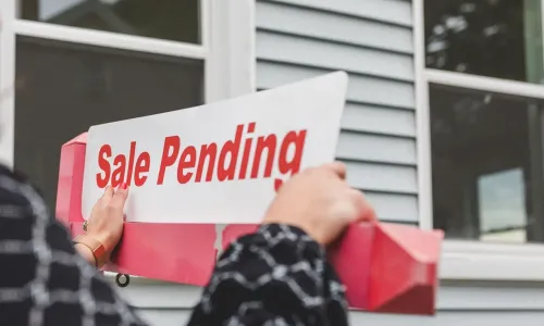 Sale pending sign in front of house window