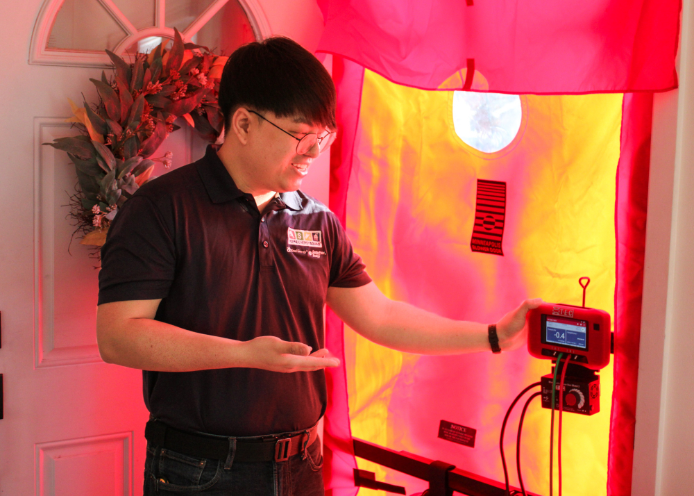 A man conducts a blower door test during a home energy audit.